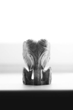 Beyaz arkaplanda doğal taştan yapılmış bir tanrı heykeli.