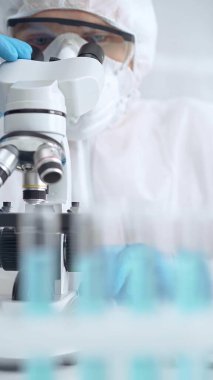 Laboratuvar ortamında mikroskop kullanarak örnekleri analiz eden bilim adamı..