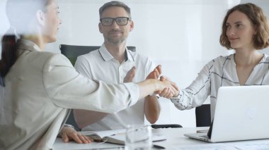Businesswomen partners are shaking hands after successful negotiation, colleagues clapping, celebrating agreement in modern office headset. Handshake concept.
