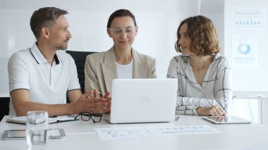 Business team collaborating on a project, analyzing data on a laptop during a productive office meeting, fostering teamwork and strategic planning