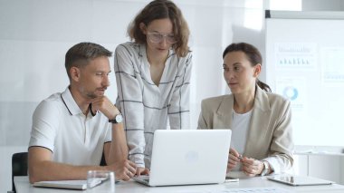 Business people team collaborating and analyzing data on a laptop during a productive meeting in a modern office, fostering teamwork and strategic decision making.