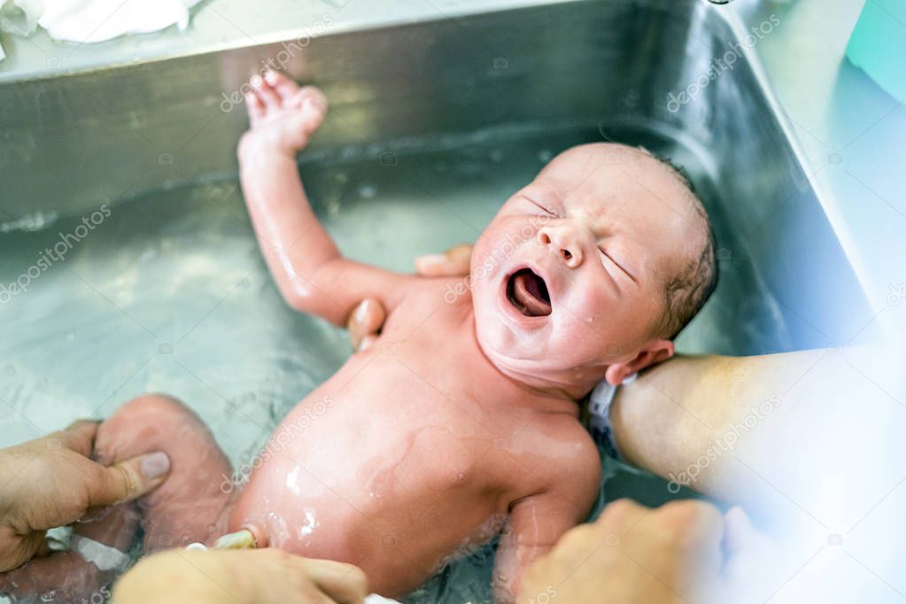 First bath of a newborn baby boy in the hospital sink