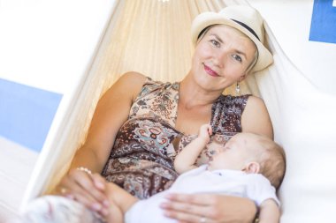 Annesi ve onun erkek evin önünde hamakta rahatlatıcı küçük bebek