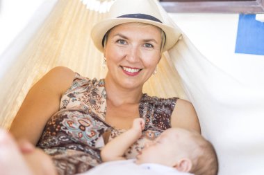 Annesi ve onun erkek evin önünde hamakta rahatlatıcı küçük bebek