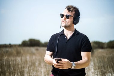 Müzik onun smartphone--dan onun kulaklıktan yakışıklı genç