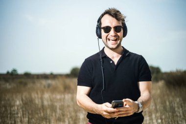 Müzik onun smartphone--dan onun kulaklıktan yakışıklı genç