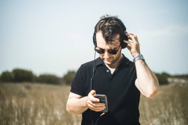 Müzik onun smartphone--dan onun kulaklıktan yakışıklı genç