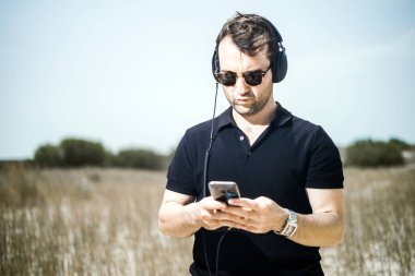 Müzik onun smartphone--dan onun kulaklıktan yakışıklı genç