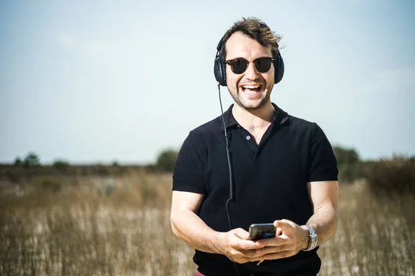 Knappe Jongeman Afspelen Van Muziek Van Zijn Smartphone Zijn Hoofdtelefoon — Stockfoto