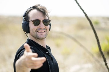 Genç çekici adam onun kulaklıklar üzerinde müzik keyfi güneş gözlüğü takıyor