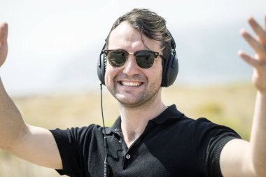 Mutlu, çekici bir adam onun kulaklıklar üzerinde müzik keyfi güneş gözlüğü takıyor