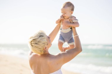 4 aylık erkek bebek ile sahilde oynarken çekici sarışın anne