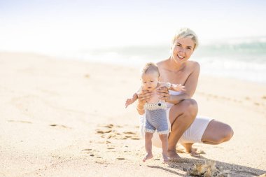 4 aylık erkek bebek ile sahilde oynarken çekici sarışın anne