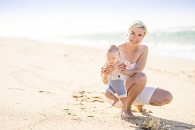 4 aylık erkek bebek ile sahilde oynarken çekici sarışın anne