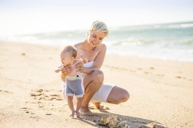 4 aylık erkek bebek ile sahilde oynarken çekici sarışın anne