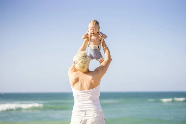 有吸引力的金发妈妈玩与4月大男婴在海滩上 — 图库照片