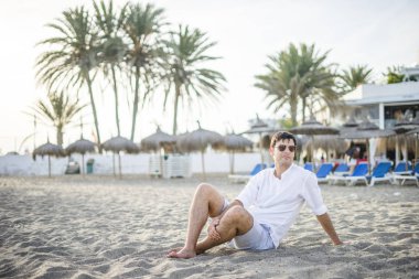 Yakışıklı adam portresi sahilde günbatımı tarafından rahat.