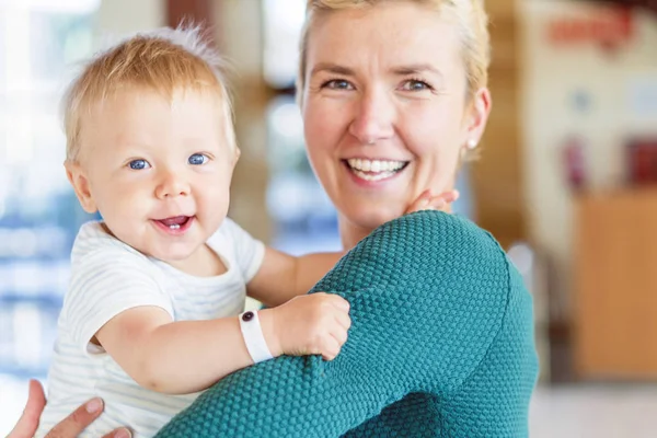 Otel lobisinde, erkek bebek tutan gülümseyen anne — Stok fotoğraf