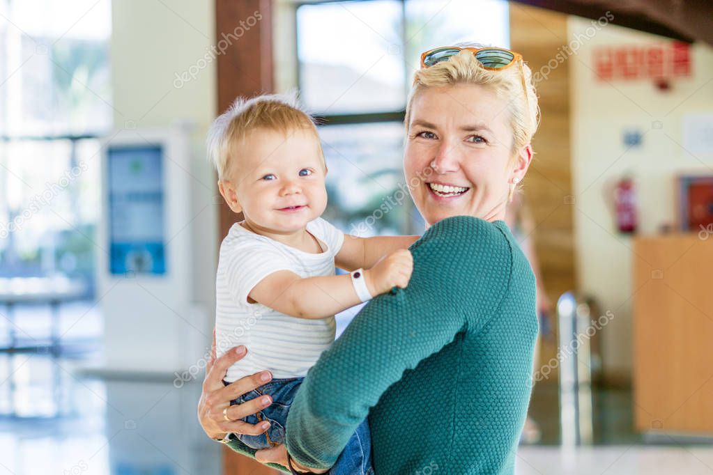 Smiling mother holding baby boy at the lobby in the hotel 
