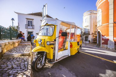 Tavira sokaklarında turistler için sarı elektrikli küçük araç,