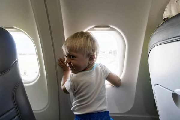 Happy one year old baby boy next to airplain 's window — стоковое фото
