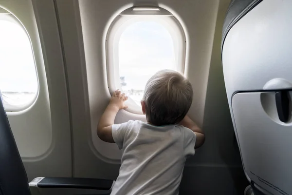 Годовалый мальчик смотрит в окно самолета — стоковое фото