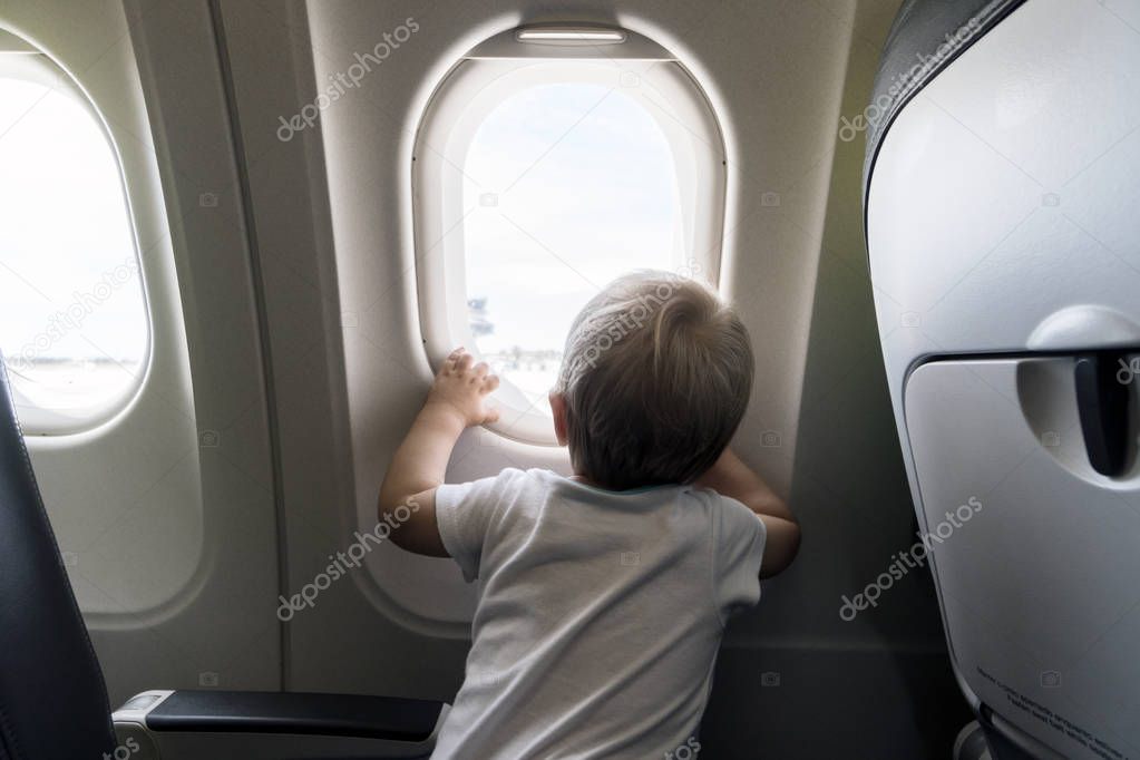 A year old baby boy looking through airplain's window 