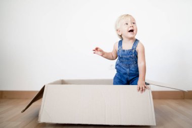 Sevimli küçük çocuk kutudan atlıyor.