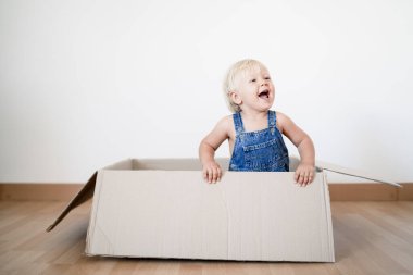 Sevimli küçük çocuk kutudan atlıyor.