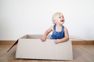 Sevimli küçük çocuk kutudan atlıyor.