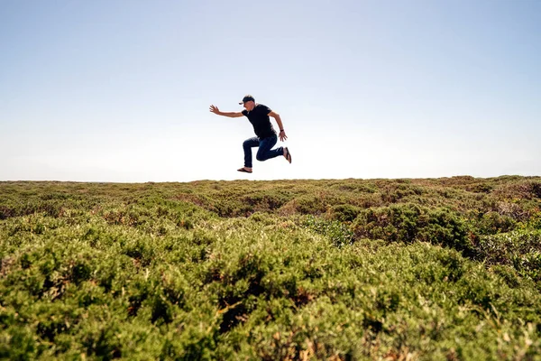 Человек Счастливо Прыгает Высоко Над Зелеными Кустами Алгарве Португалия — стоковое фото