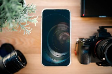 Teknoloji. Ahşap masaüstünde akıllı telefon, dslr kamera ve lenslerin üst görünümü. 