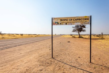 Namibya 'daki Solitaire araba mezarlığı - 27 Ağustos 2025: küçük çöl binaları yakınlarındaki paslı klasik arabalar, kum tepeleri ve dağlara karşı dizilmiş, çöl cazibesini ve izolasyonu yakalayan.