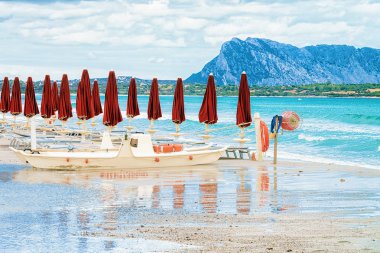 Beyaz şemsiye ar La Cinta Beach'te San Teodoro, Sardunya, İtalya. Arka planda Tavolara Adası