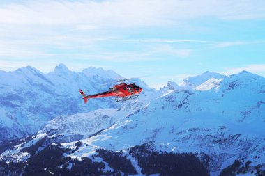 Maennlichen, İsviçre - 31 Aralık 2013: Kışın, İsviçre Maennlichen Swiss Alpine dağın üstünden uçan kırmızı helikopter