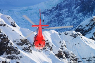 Maennlichen, İsviçre - 31 Aralık 2013: Kışın, İsviçre Maennlichen İsviçre Alpleri dağın üstünden uçan kırmızı helikopter