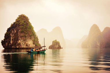 Halong, Vietnam - 23 Şubat 2016: Balıkçı teknesi, Ha Long Bay, Vietnam gün batımında. Arka planda kireçtaşı Adaları