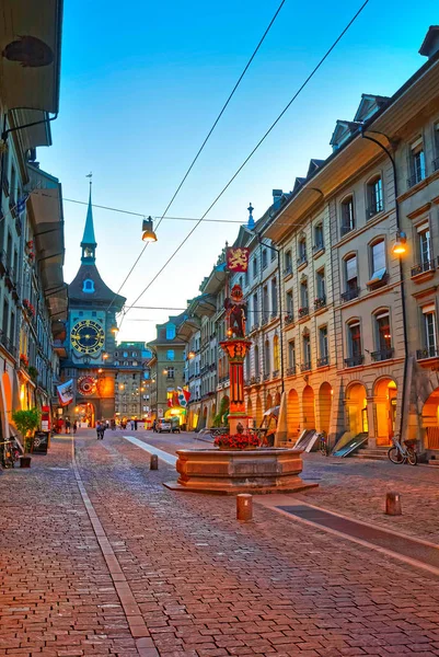 Bern, İsviçre - 21 Ağustos 2013: Zahringen Çeşmesi ve Zytglogge Saat Kulesi eski şehir merkezi Bern, İsviçre Kramgasse Caddesi üzerinde. Akşamları