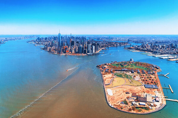 Aerial view on Governors Island and Manhattan in the foreground, New York, USA. Located in Upper New York Bay, Governors Island is home to historical fortifications Fort Jay and Castle Williams