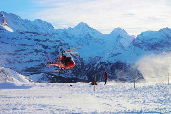 Maennlichen, Switzerland - December 31, 2013: Red helicopter flying at Swiss Alpine mountains Maennlichen, in winter, Switzerland