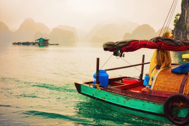 Gün batımında balıkçı teknesi Ha Long Bay, Vietnam üzerinde. Arka planda kireçtaşı Adaları