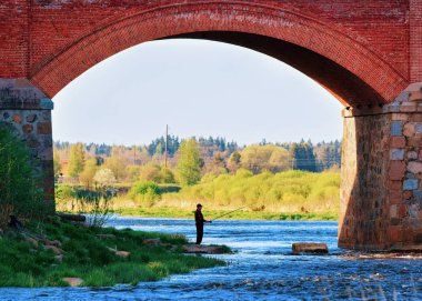 Kuldiga, Letonya - 5 Mayıs 2016: Batı Letonya'daki Kurzeme'deki Kuldiga'daki Ventas Rumba şelalesinde köprünün altında nağme balıkçı. Şehrin adı Goldingen'di..