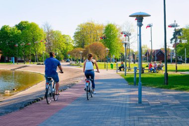 Nida, Litvanya - 10 Mayıs 2016: Bisiklete binen çift. Neringa Klaipeda yakınlarındaki Nida tatil kasabası, Curonian Spit ve Litvanya Baltık Denizi.