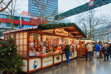 Berlin, Almanya - 11 Aralık 2017: Almanya'nın Kış Berlin kentindeki Kaiser Wilhelm Memorial Kilisesi'nde Noel Pazarı'nda tatlılarla ayakta duran insanlar. Advent Fuar Dekorasyon ve El Sanatları Öğeleri ile Tezgahları