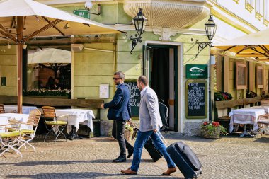 Ljubljana, Slovenya - 27 Nisan 2018: Slovenya'nın tarihi merkezinde sokakta bavulları olan iki işadamı