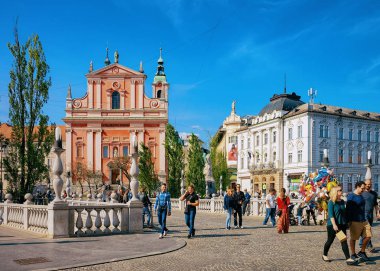 Ljubljana, Slovenya - 27 Nisan 2018: Slovenya'nın Ljubljana'nın tarihi merkezinde ki Fransisken Annunciation Kilisesi ve Üçlü Köprü'deki insanlar