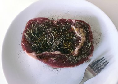 Çatallı beyaz tabakta çiğ biftek. Görünümü kapat