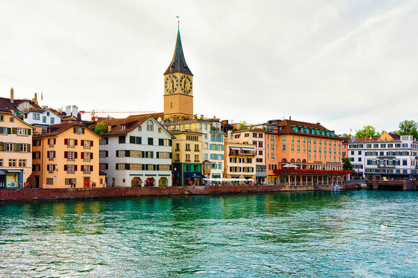Zurich, Switzerland - September 2, 2016: St Peter Church at Limmat River quay in the center of Zurich, Switzerland. People on the background