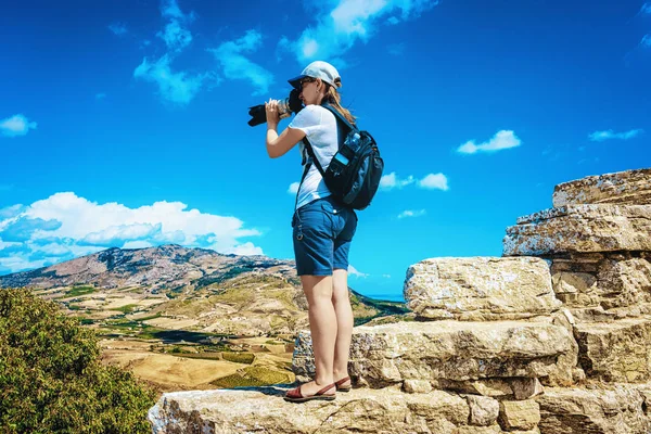 Sırt çantalı bir kadın İtalya 'nın Sicilya adasındaki Yunan tiyatrosunda Segesta manzarasına bakıyor.