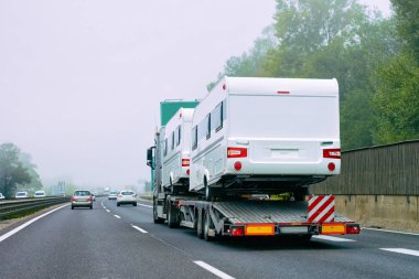 Slovenya asfalt yolda motorlu evler rv ile kamyon taşıyıcı.